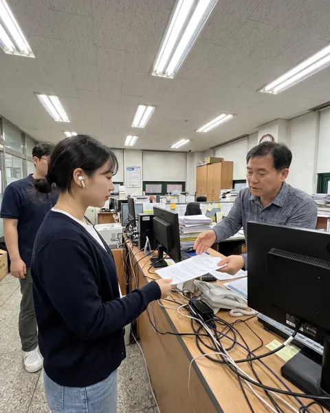 A woman wearing earbuds at an office front desk in Seoul